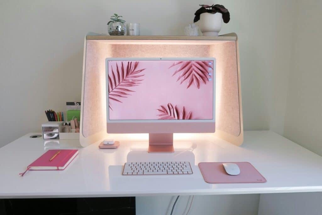 image décorative : ordinateur avec fond rose et feuilles roses, clavier rose, tapis de souris rose et souris blanche